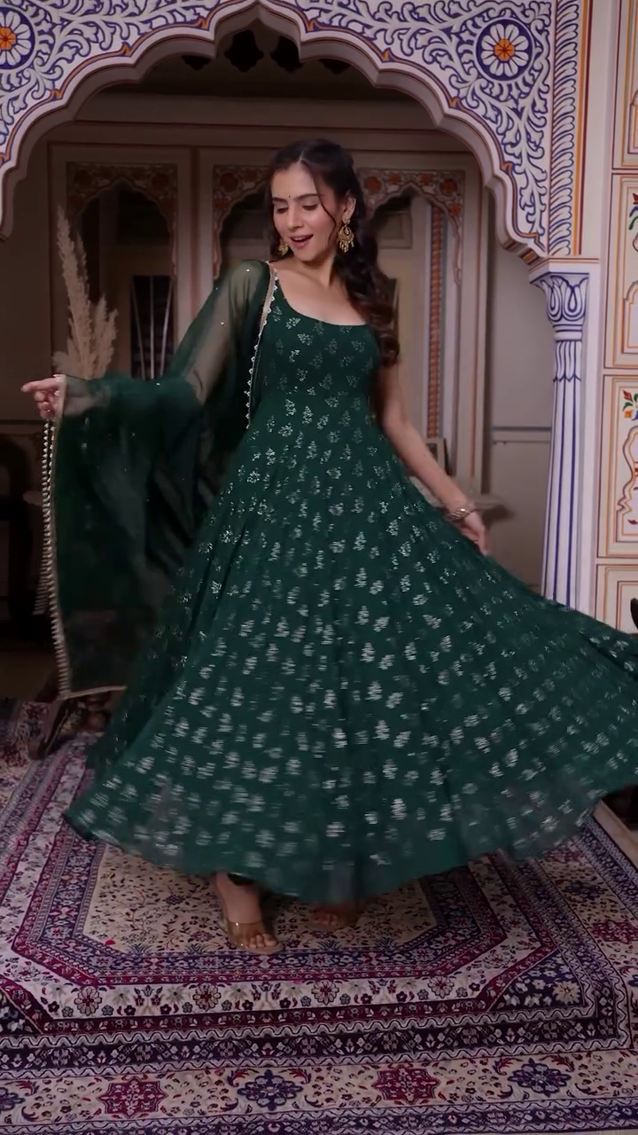 Elegantly Twirling in a Rich Green Anarkali Dress Adorned with Delicate Silver Embroidery, Paired with a Sheer Green Dupatta, Radiating Grace and Charm in a Traditional Setting