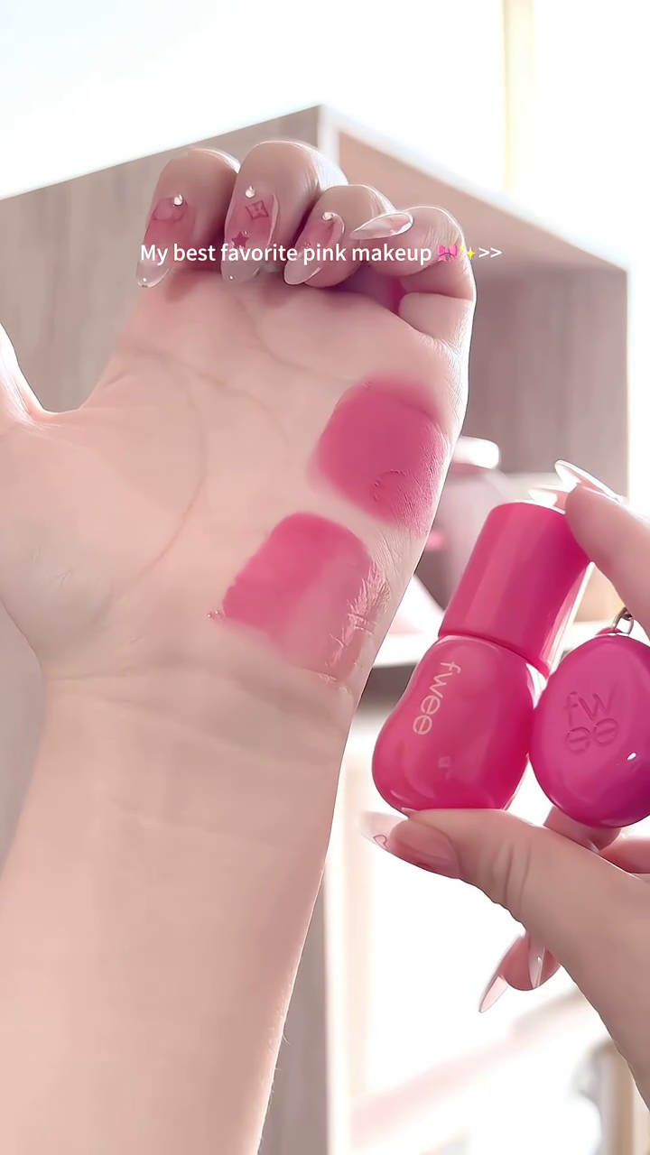 A collection of my favorite pink makeup shades, featuring a vibrant pink lip product in a cute bottle, swatched beautifully on the hand for a soft yet bold pink finish.