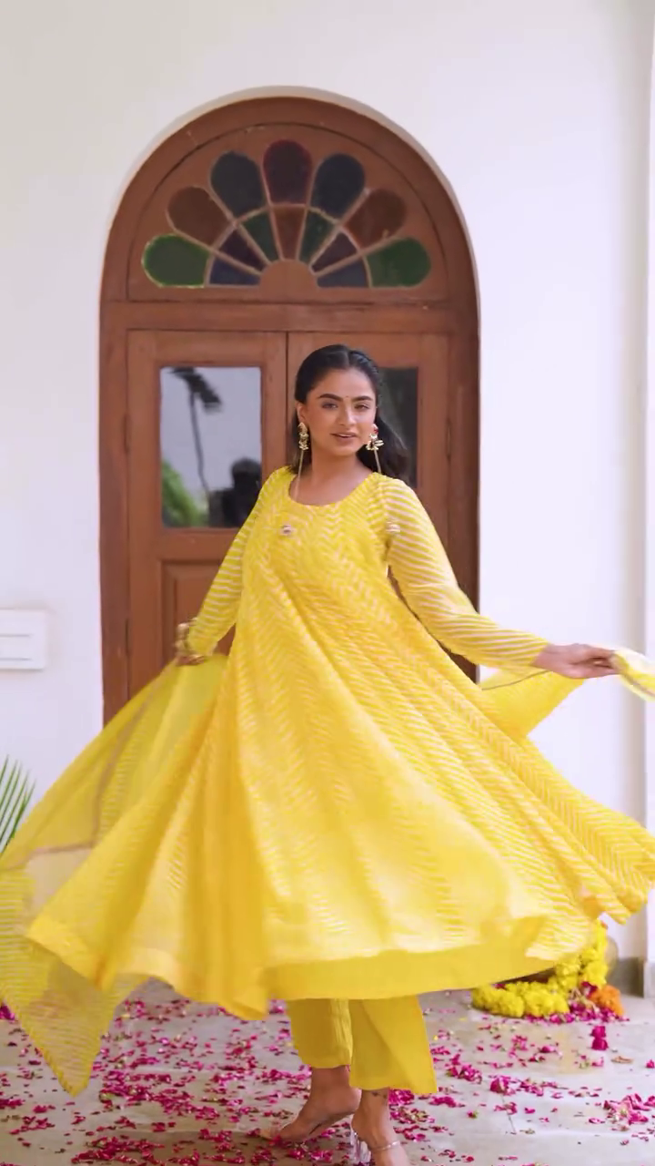 A vibrant yellow ethnic outfit with a flowing kurta and matching pants, featuring subtle patterns and a graceful dupatta, perfect for festive or traditional occasions.