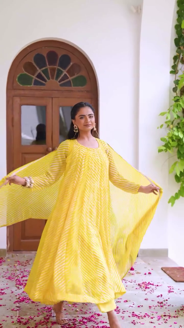 A vibrant yellow ethnic outfit with a flowing kurta and matching pants, featuring subtle patterns and a graceful dupatta, perfect for festive or traditional occasions.