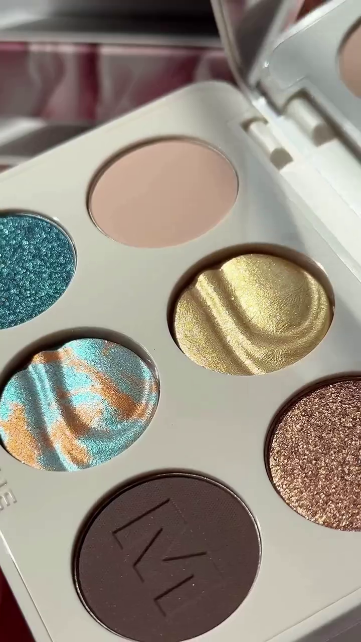 Swatches of Vibrant Eyeshadow Shades from the Morphe Palette, Featuring Sparkling Teals, Shimmery Oranges, Golds, and a Rich Brown, Perfect for Creating Stunning Eye Looks