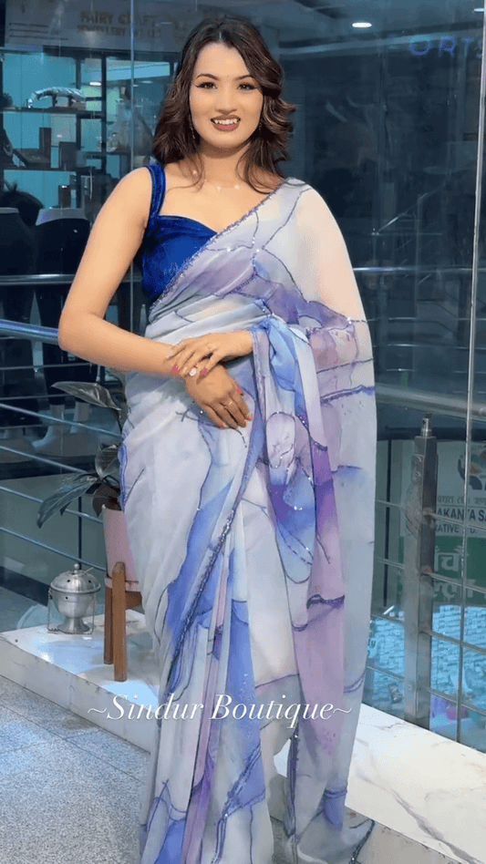 White and Lavender Shaded Organza Saree with Abstract Watercolor Print and Subtle Sequin Detailing Paired with Rich Royal Blue Velvet Blouse – A Graceful Blend of Modern Artistry and Traditional Charm